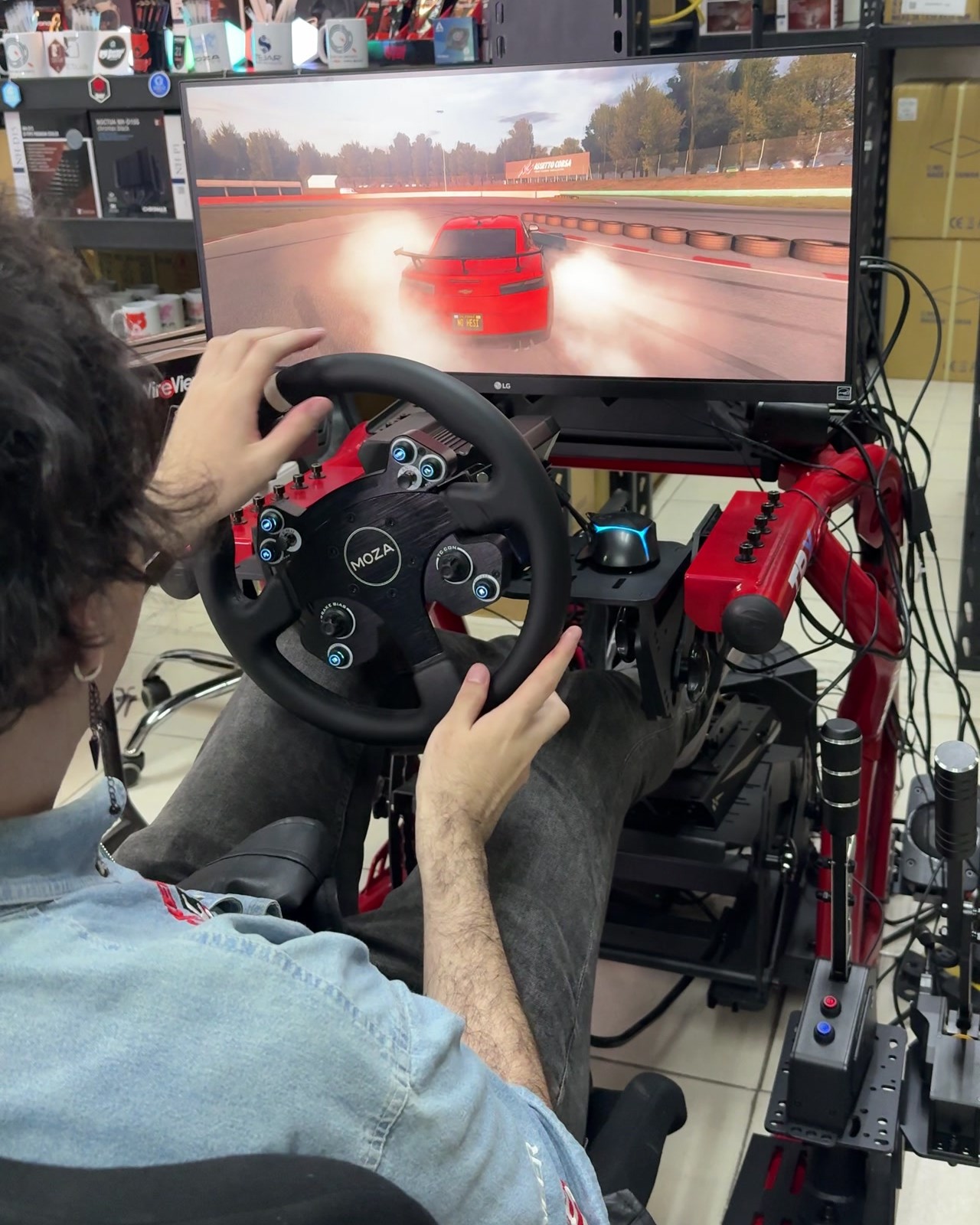 David Tapia haciendo drift en Assetto Corsa con un volante Moza, con un coche rojo en la pantalla.